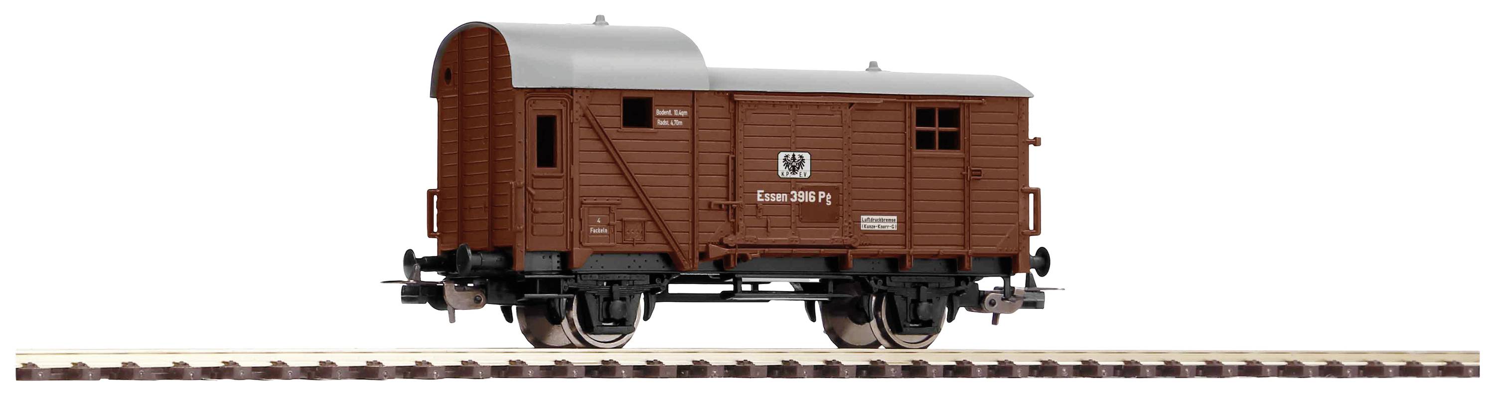 A brown goods wagon with the marking 'Ommbu 33 802' is standing on a track. The wagon has a curved roof and sliding doors.