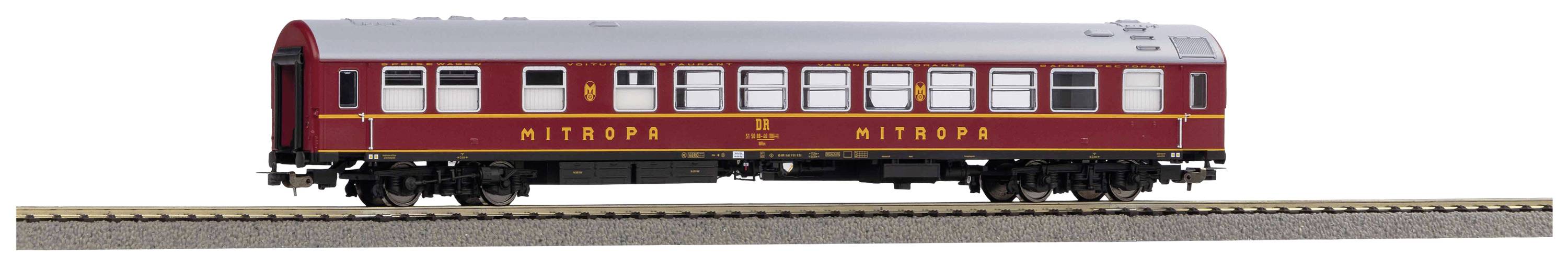 Red model train carriage to scale on track with 'Mitropa' inscription. Vehicle has many windows and a silver roof.