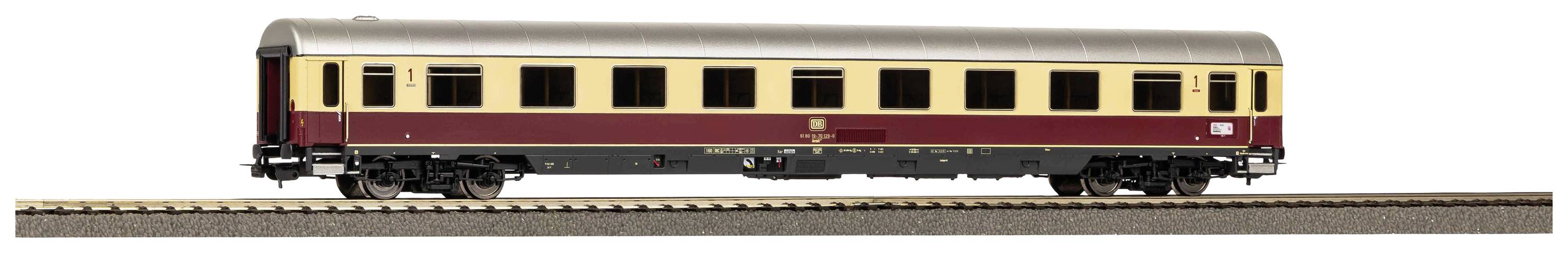 A model railway passenger carriage, painted burgundy and beige, stands on a track. The carriage has multiple windows and detailed markings.