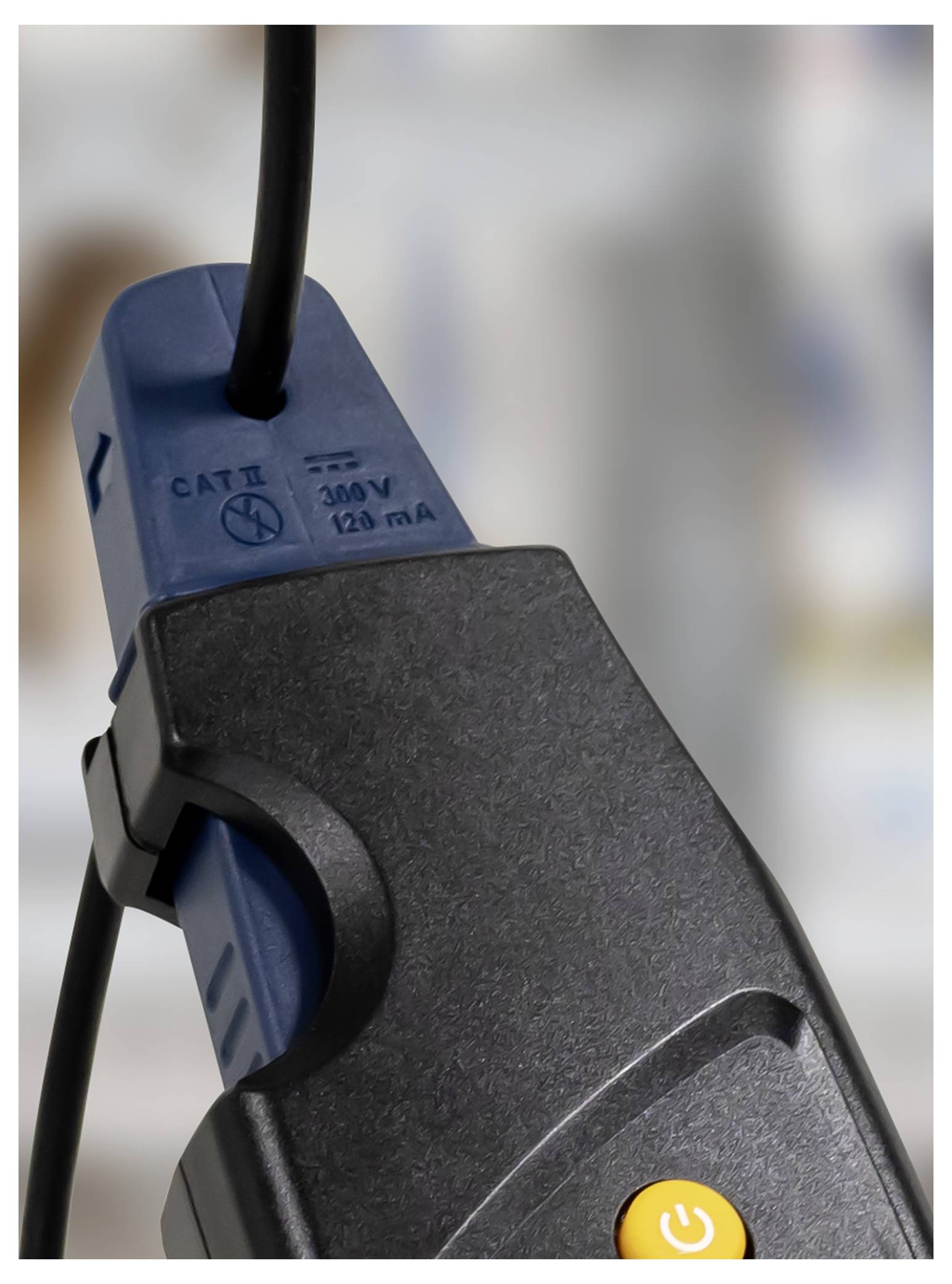 Close-up of a black and blue power clamp with a yellow power button and cable attached.