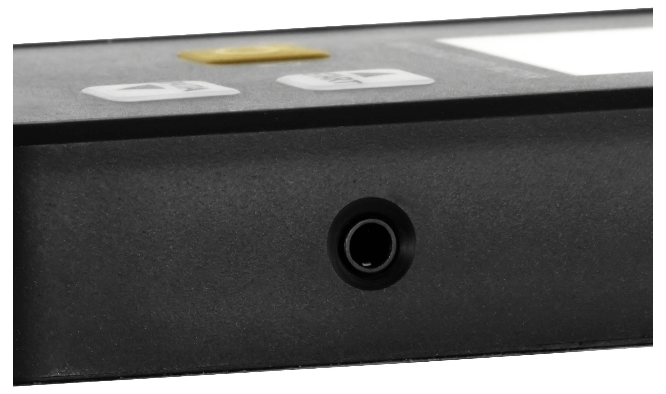 Close-up of a black electronic device panel with a round headphone or audio jack centered near the bottom edge.