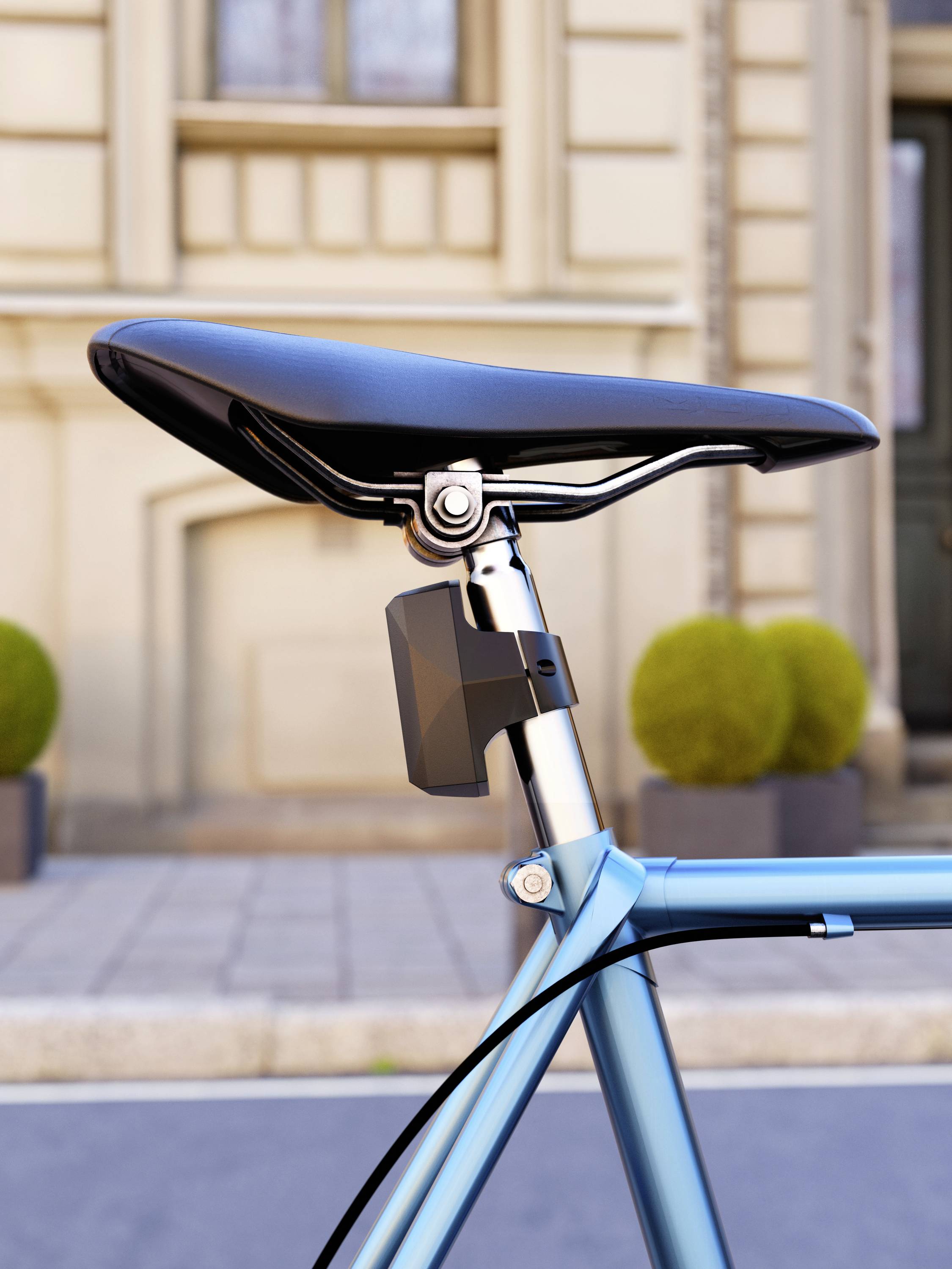Bicycle seat of a blue bicycle, which is parked on a cobblestone street in front of a historic façade with round plant pots.