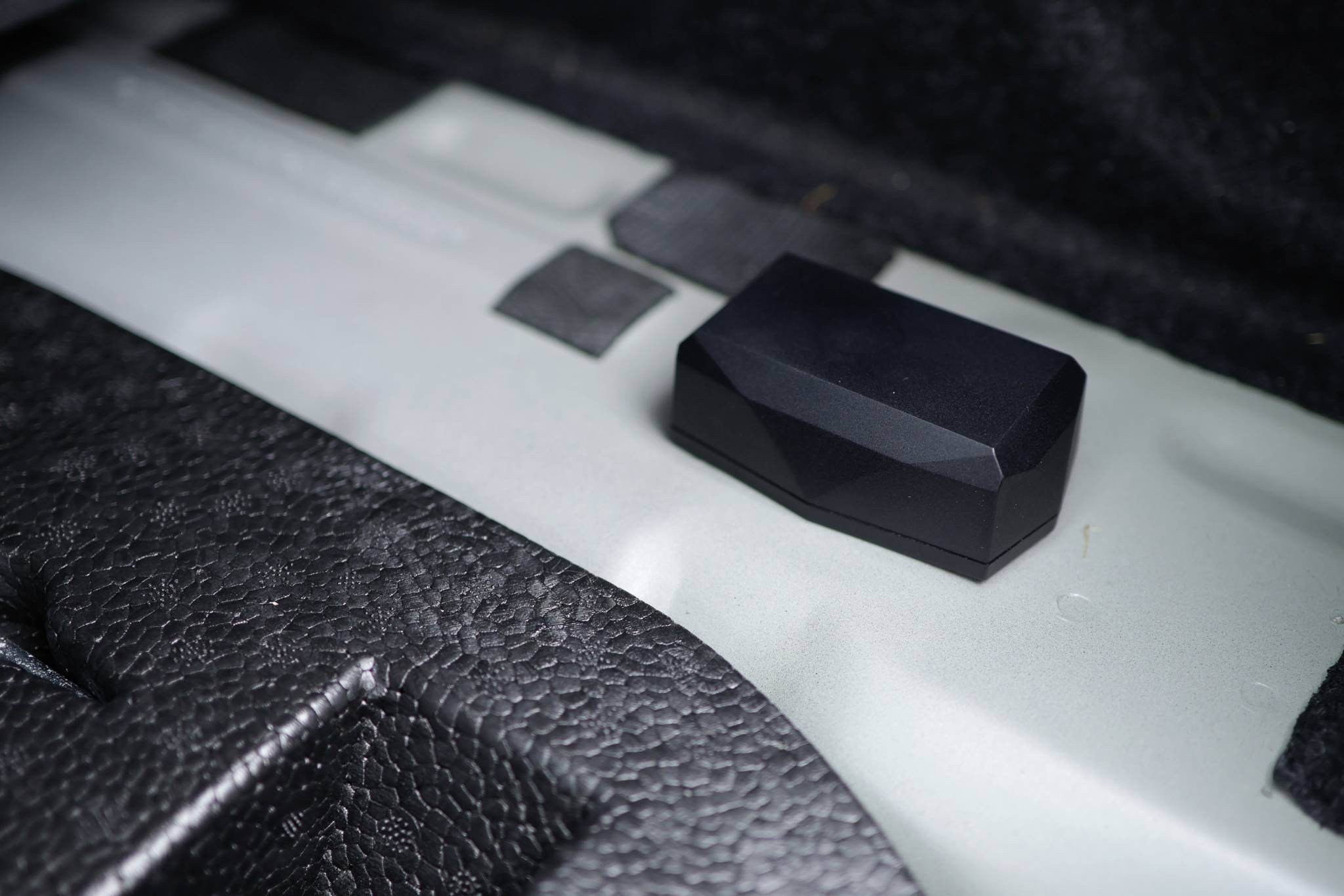 A black rectangular object on a metallic, textured surface inside a vehicle.