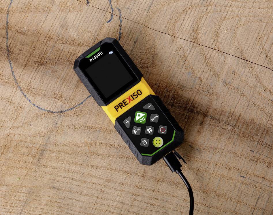 A digital measuring device with a screen and buttons lies on a wooden floor. It is connected by a cable and displays 'P 1000'.