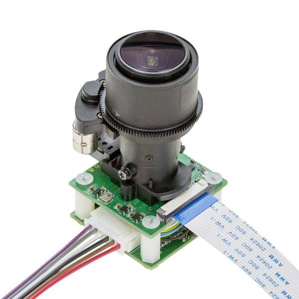 Camera lens mounted on a green circuit board with a ribbon cable and colourful wires for electronic applications.