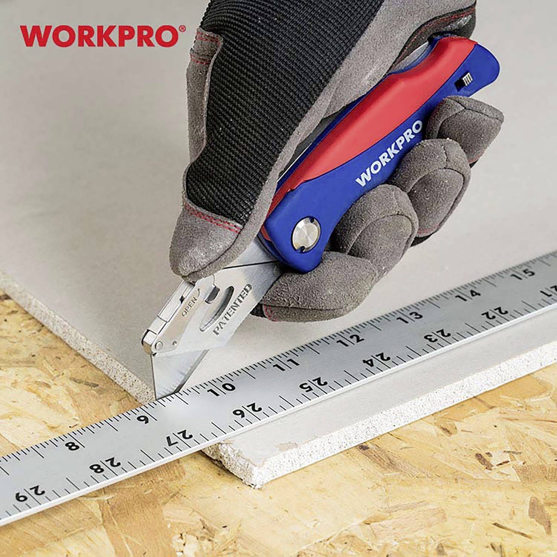 A gloved hand holds a blue and red hobby knife by the brand 'WORKPRO', cutting along a metal ruler across a plasterboard sheet.