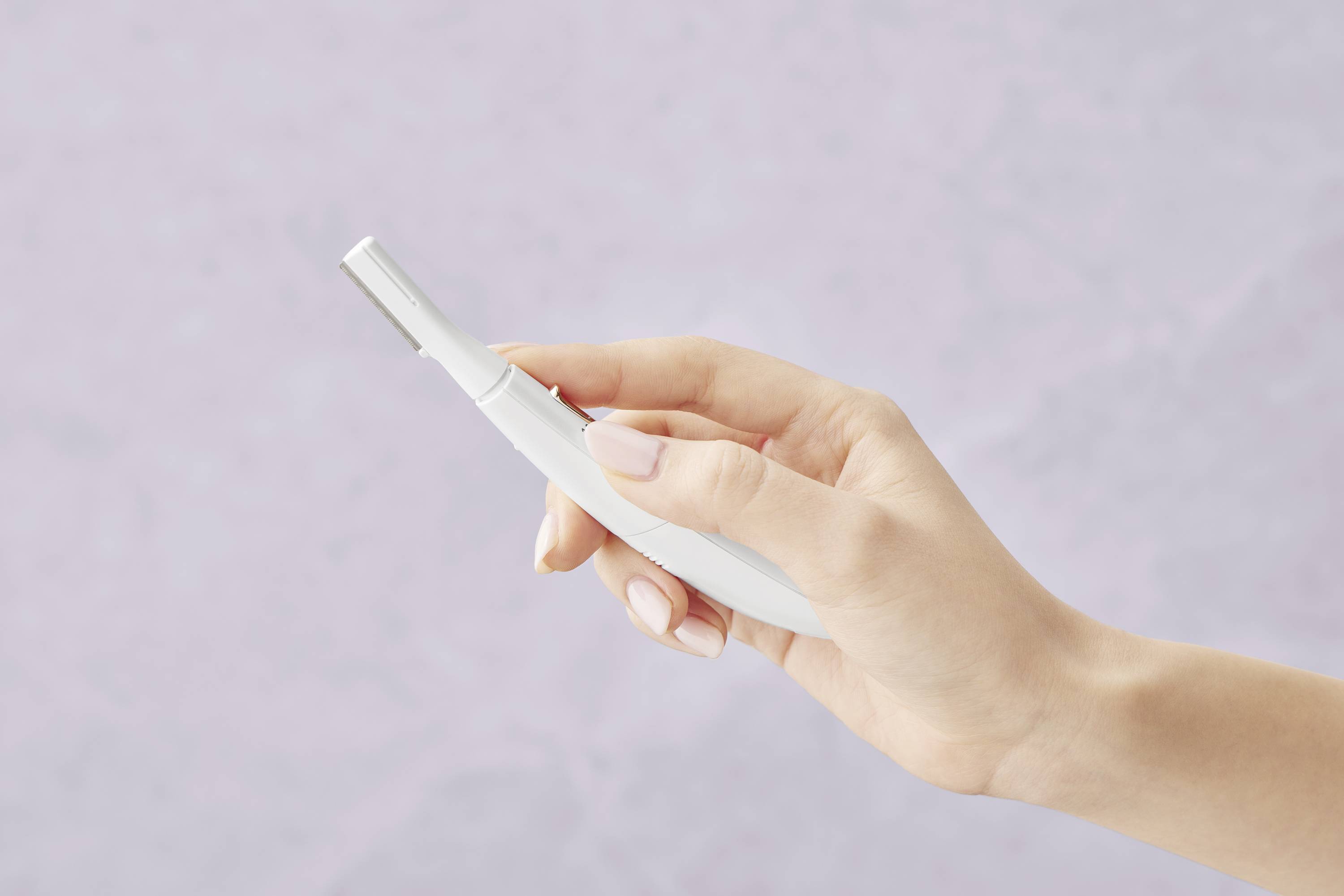 A hand holds a white electronic beard trimmer against a neutral, light lilac background.