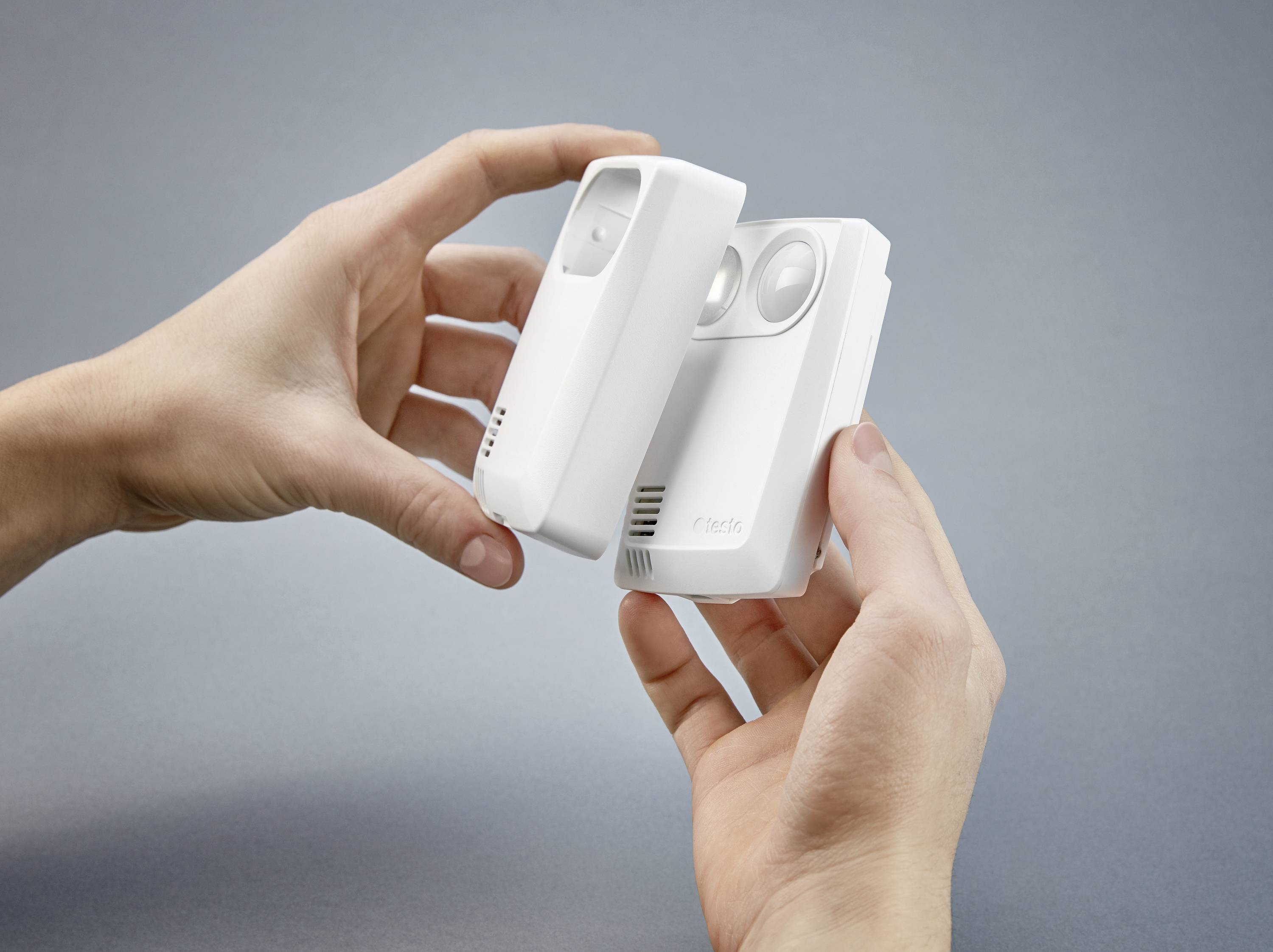 Two hands are holding a wireless doorbell and a motion sensor.