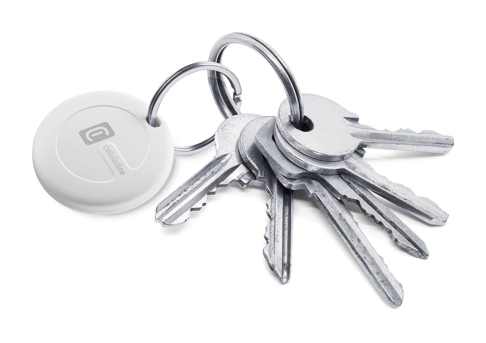 A keyring with five silver keys and a round, white chip tag on a white background.