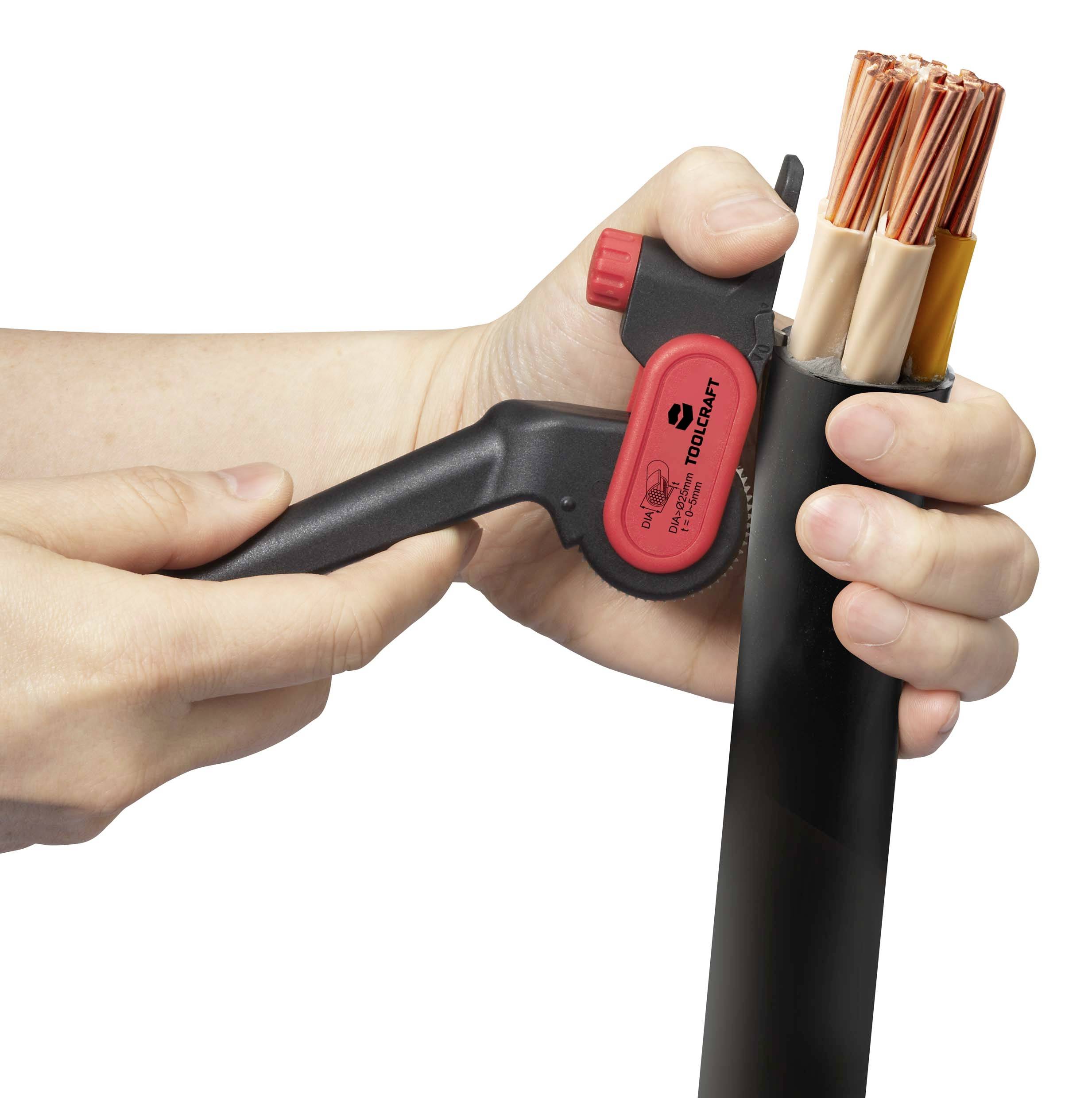A person is holding a wire stripping tool in their left hand and stripping the outer sheath of a thick cable with multiple copper conductors in their right hand.