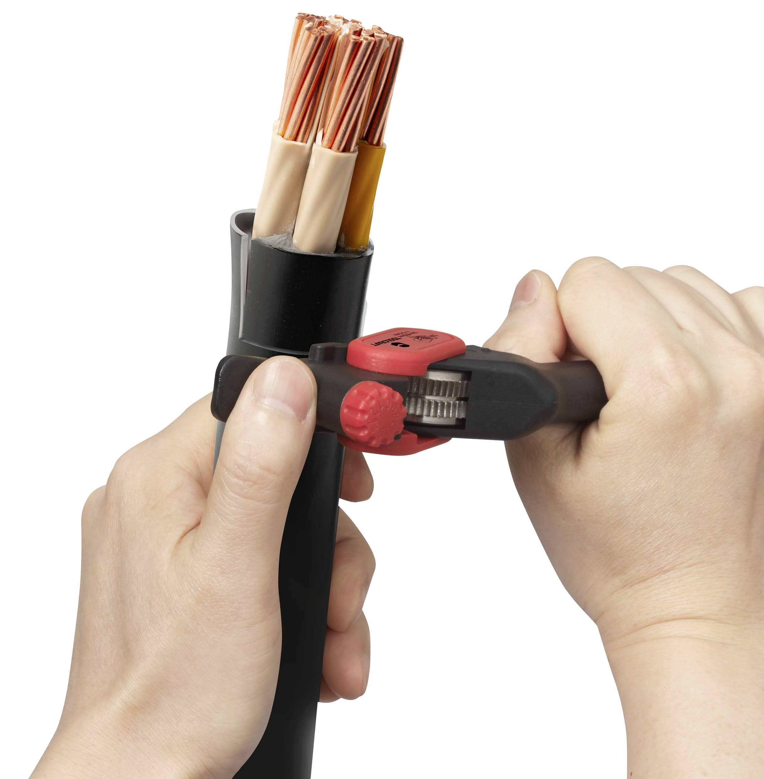 A person is holding a thick cable and cutting it with a red cable cutter. The cable cross-section reveals copper wires.
