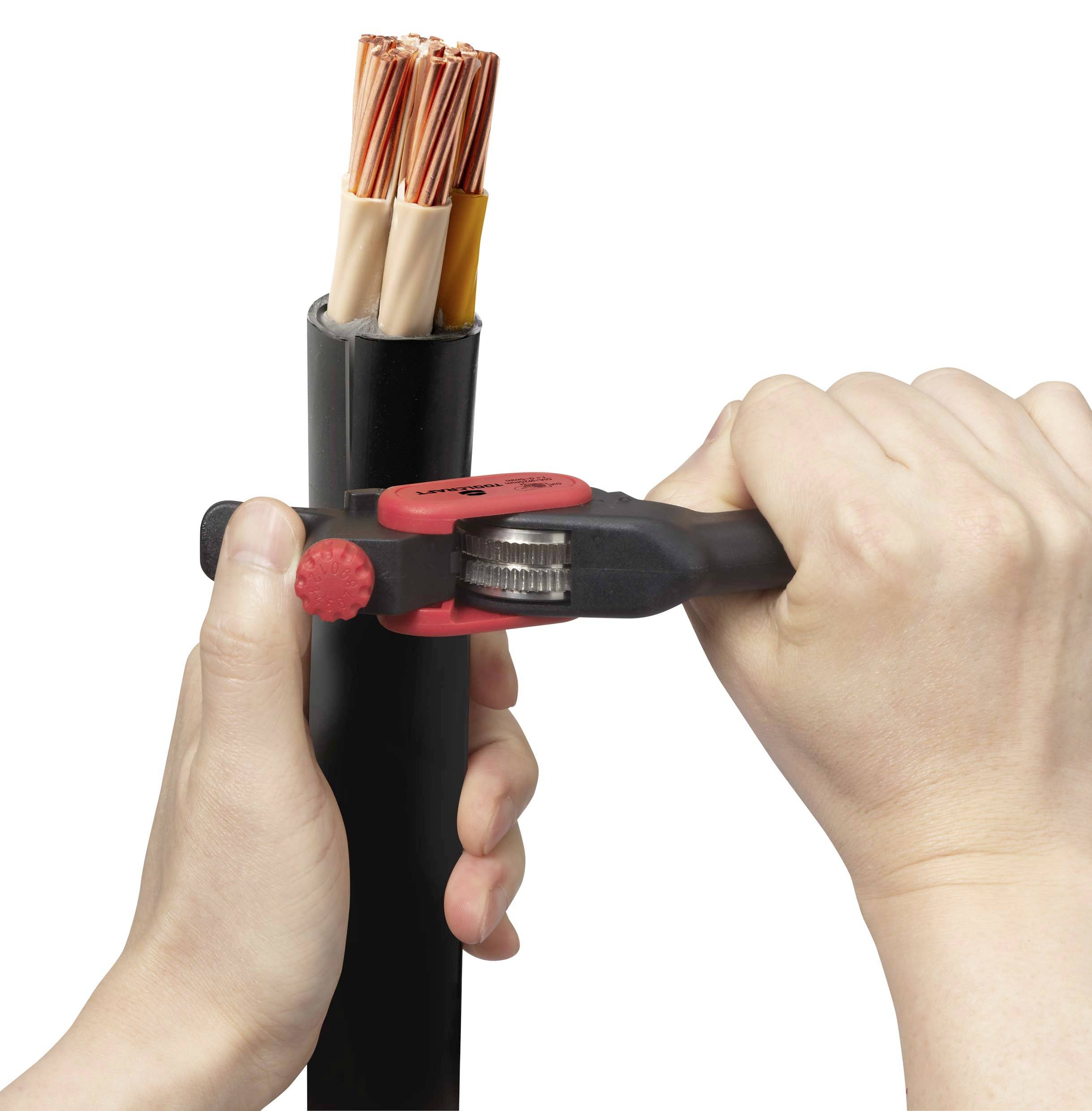 Two hands use a tool to strip a black cable, revealing the internal copper wire strands.