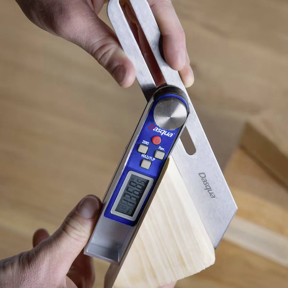 A person is measuring the angle of a piece of wood using a digital angle measurer. The display shows the current angle value.