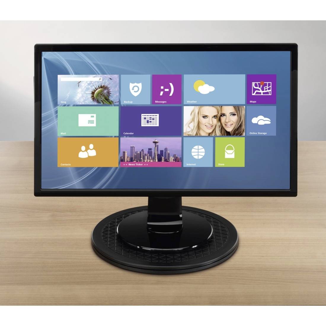 A computer screen displays a tiled interface with icons for apps and widgets on a wooden table.