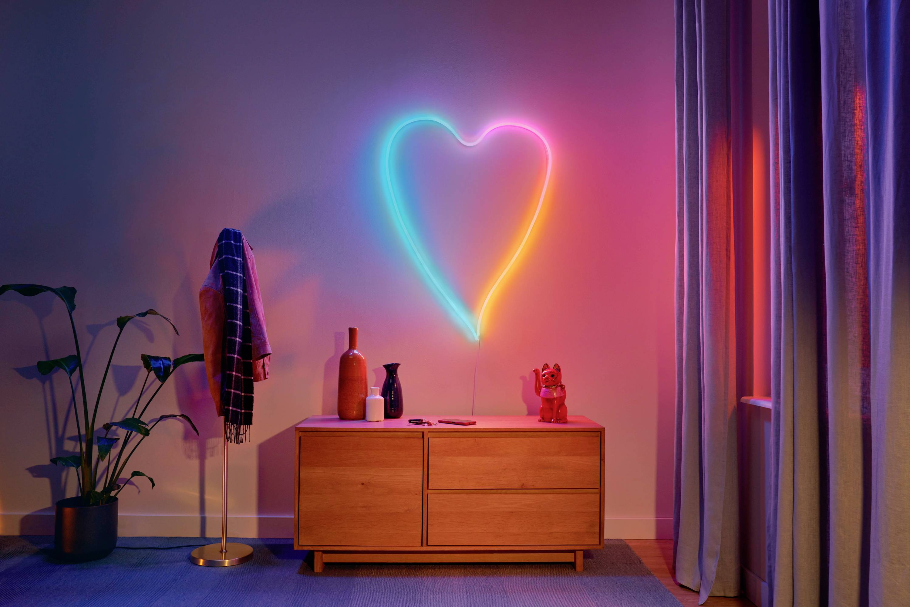 A living room with a chest of drawers, on which various decorative items are placed. A neon-coloured heart glows on the wall.