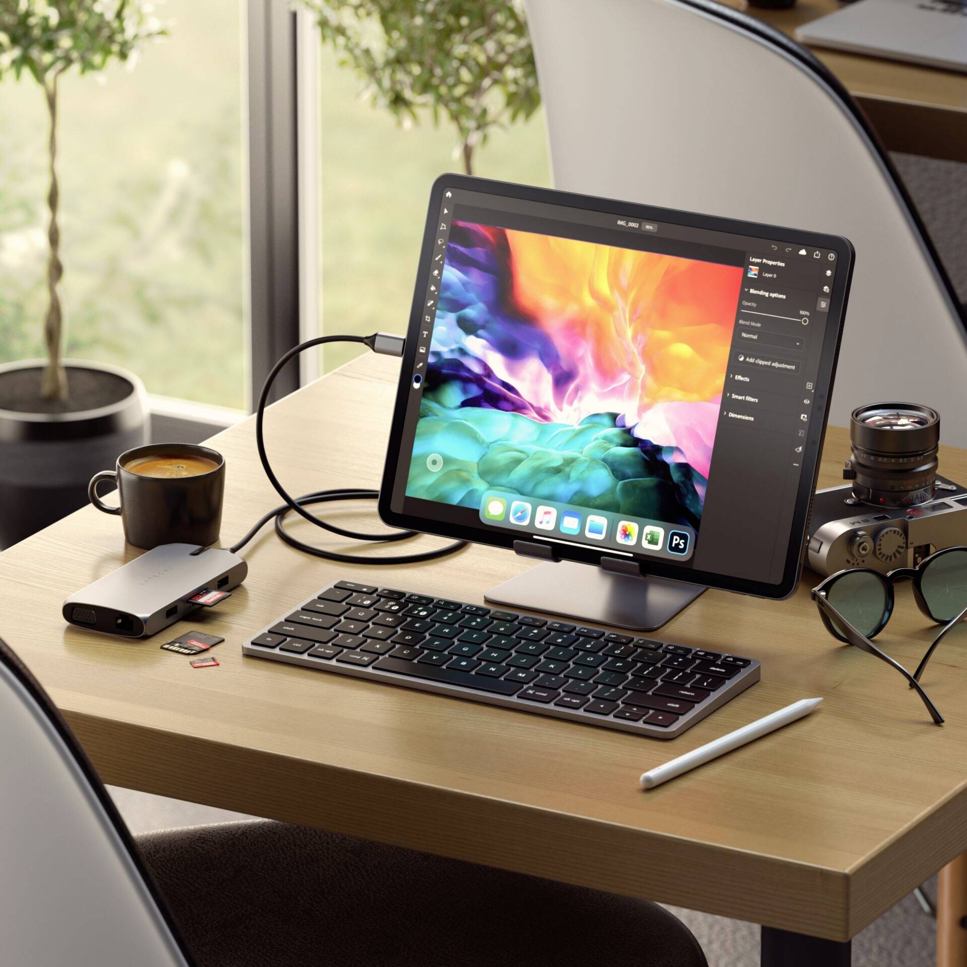 Tablet with a colourful graphic on a desk, connected to a keyboard and mouse. Beside a coffee mug and plants in the background.