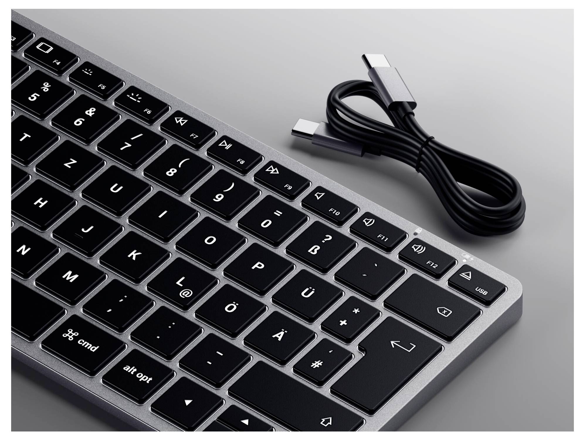 Wireless keyboard with black keys and silver frame, alongside a USB-C cable.
