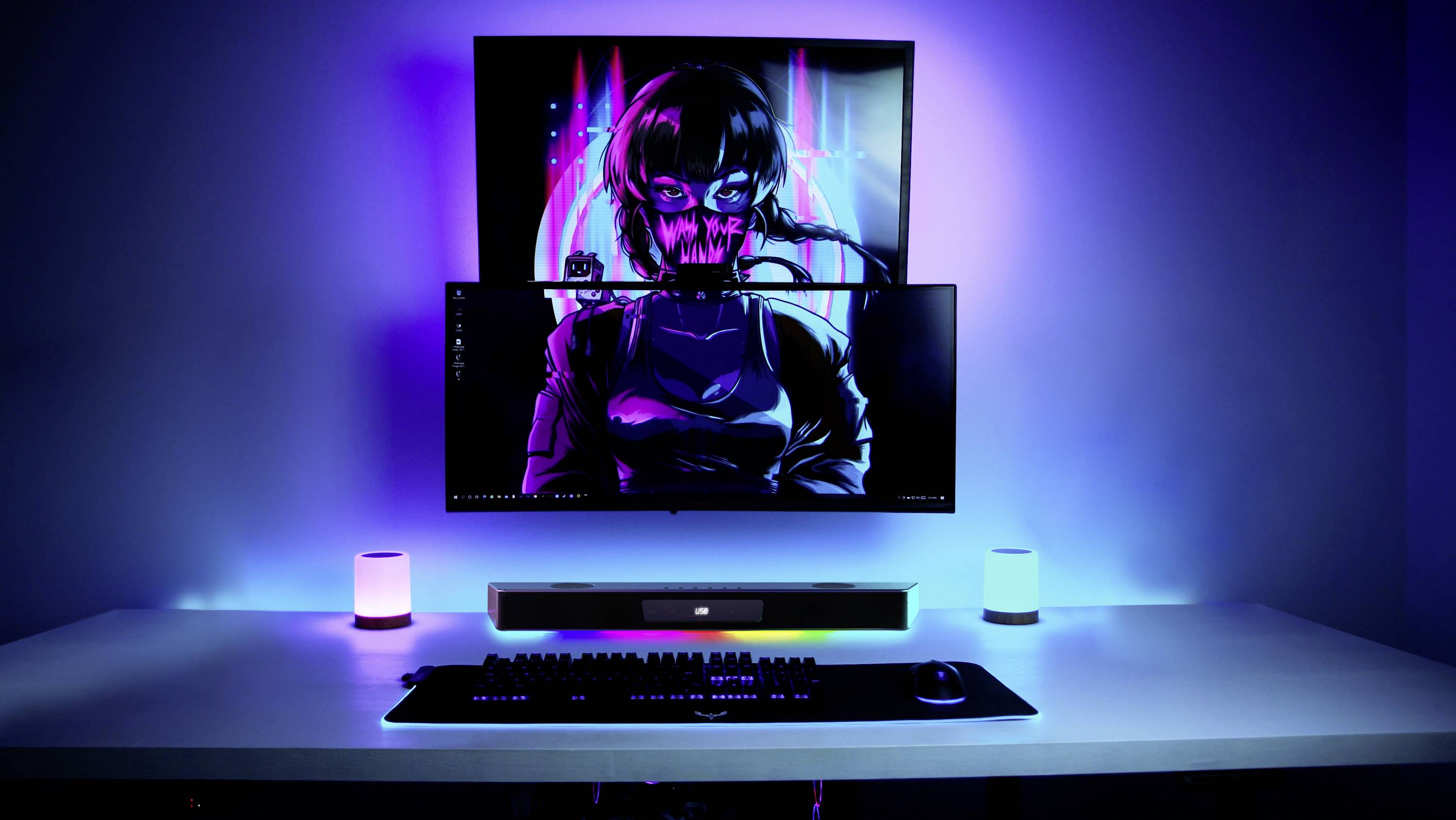A modern computer workstation with two monitoring screens. The screens display a cyberpunk design. Environment illuminated in blue.