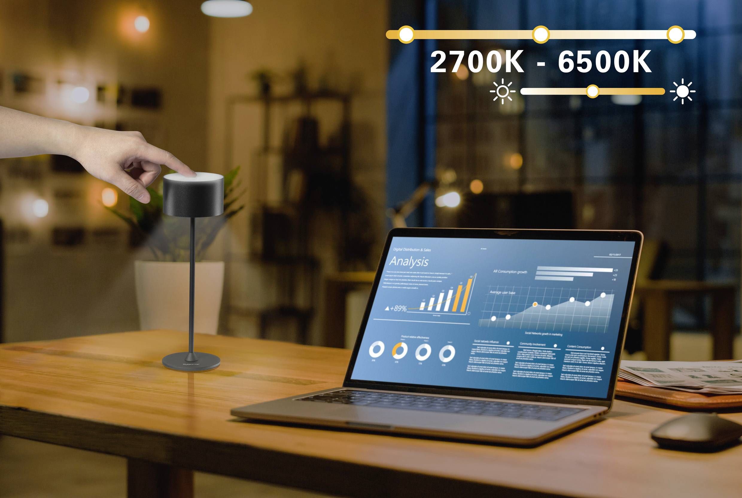 A hand touches a lamp on a table next to a laptop with data analysis charts on the screen; inscription '2700K - 6500K'.