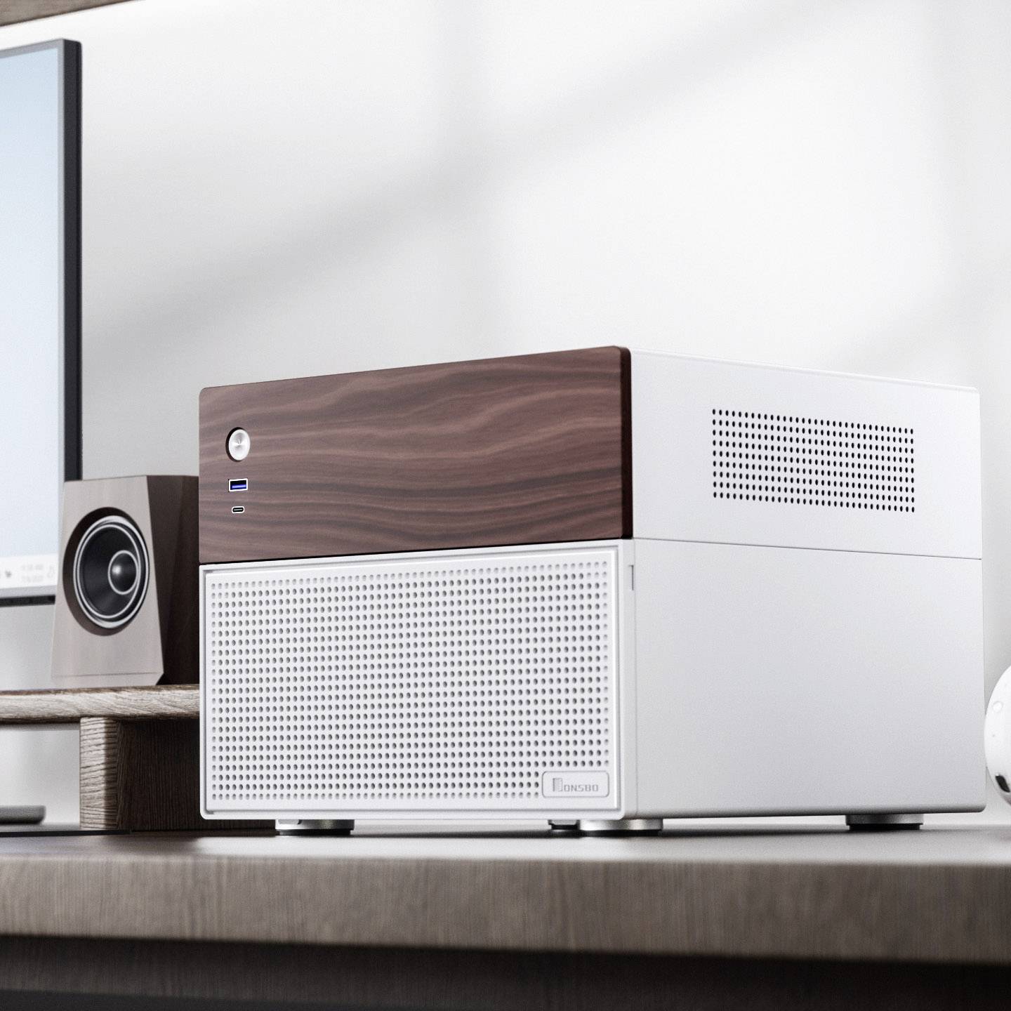 A modern computer case with a wood-effect finish sits on a desk next to a monitor and a speaker.