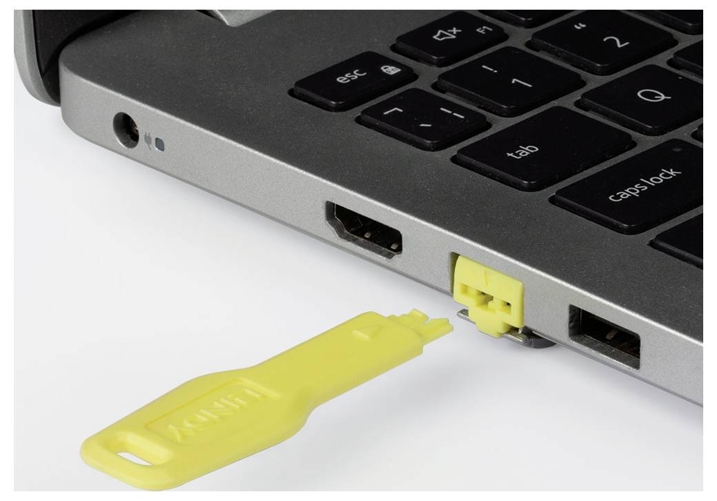 Close-up of a laptop with a yellow USB security key inserted into a side port.