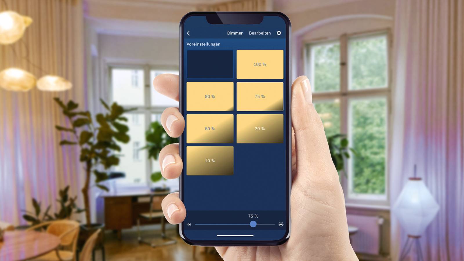 A smartphone is being held in a living room and displays an app for controlling light intensity in percentage.