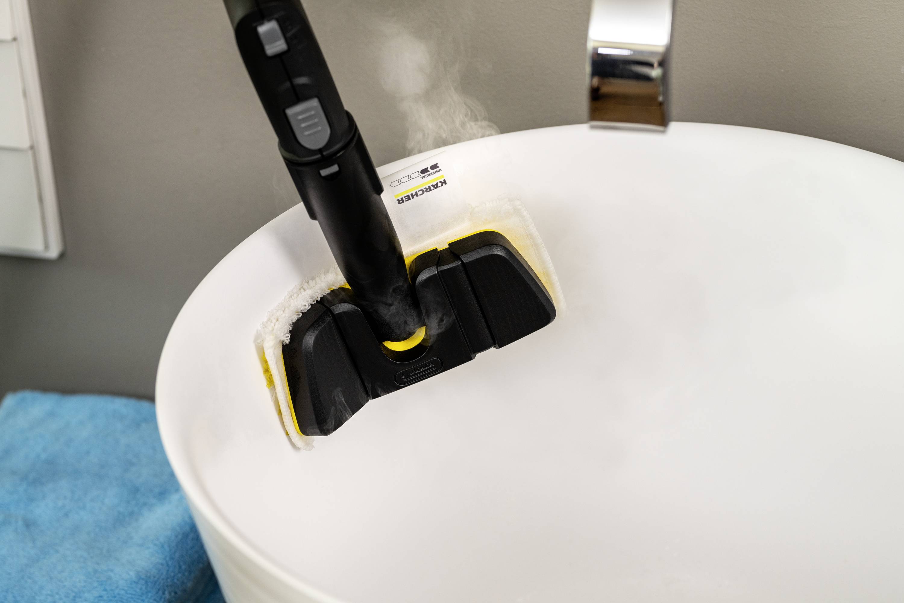 Steam cleaner is used in sink; steam visible; cleaning of sanitary facilities.