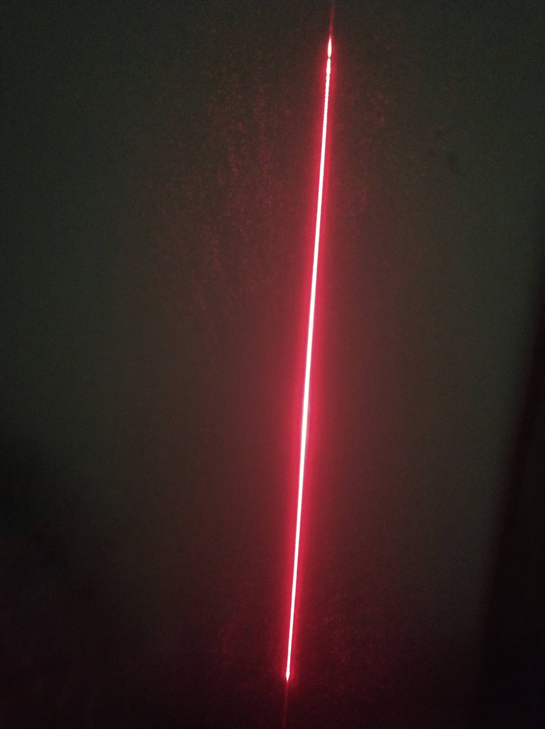 A straight, red laser beam shines vertically against a dark background. The beam is clear and intense.