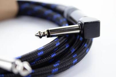 A black audio cable with blue stripes and a metal plug, coiled up on a white surface.