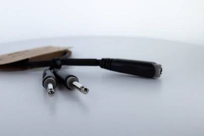 A Y-cable adapter with two plugs and one socket on a smooth surface, suitable for connecting multiple audio devices.