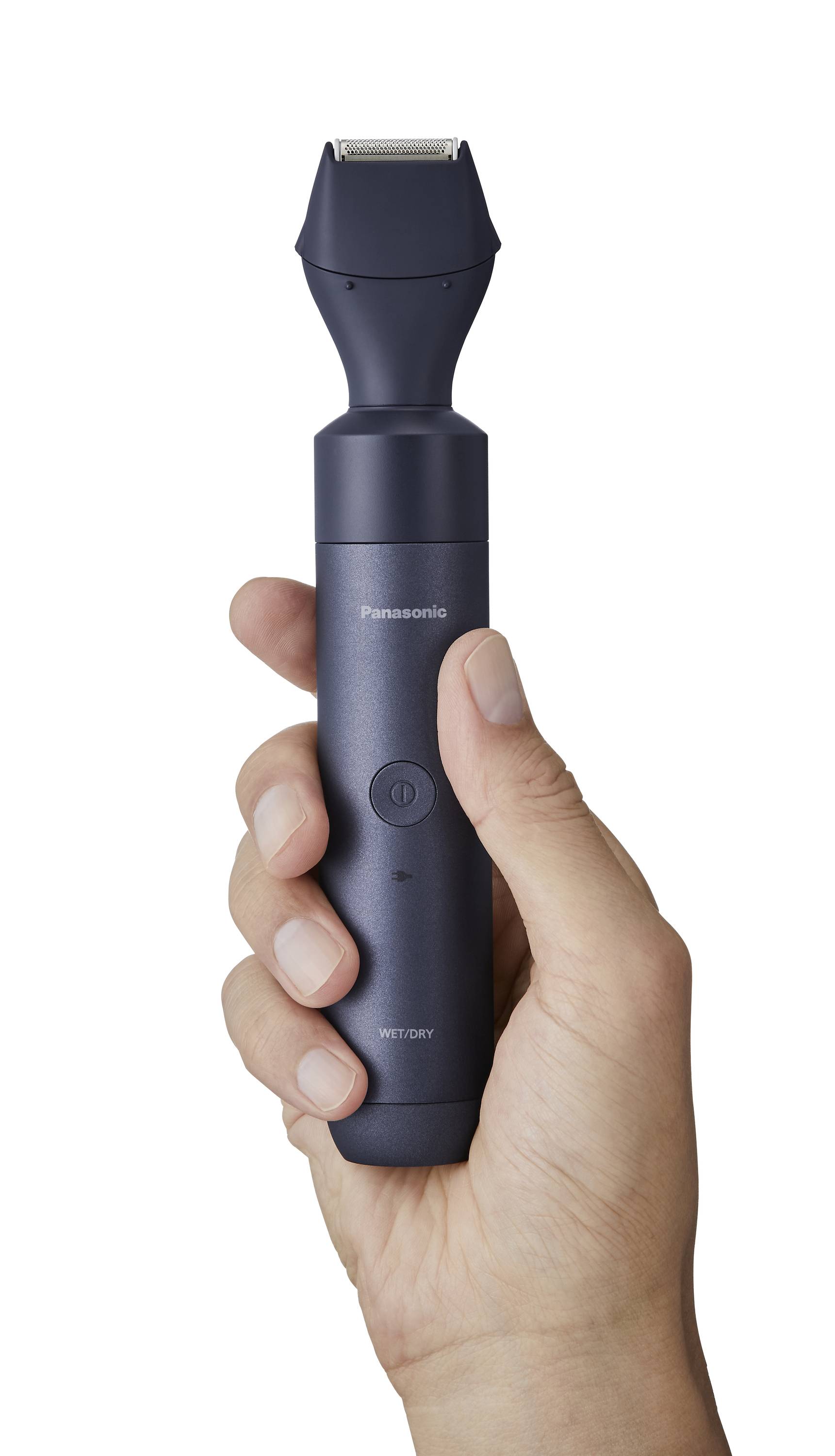 A hand is holding a dark grey electric trimmer. The trimmer has a round button and a curved cutting mechanism.