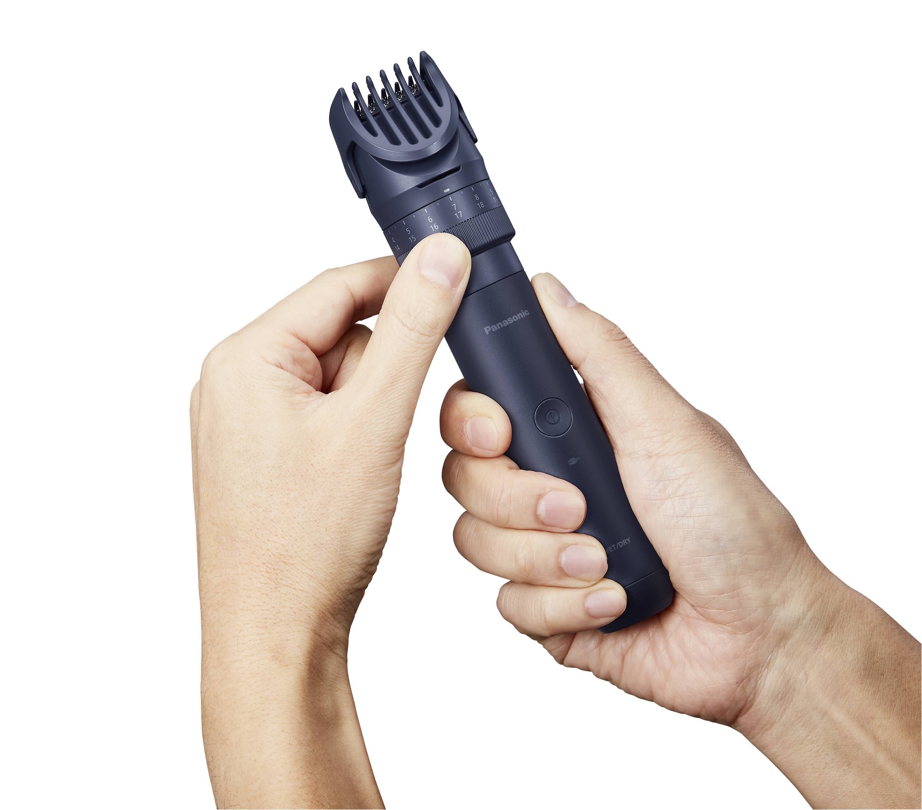 A person is holding a dark electric razor with an adjustable comb, ready for use.