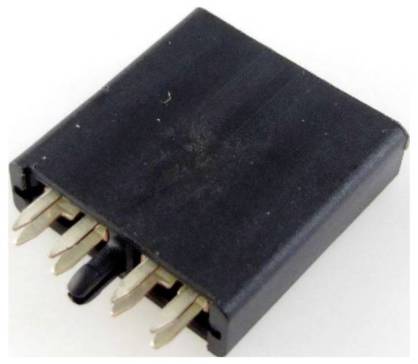 A black, four-pole jumper plug for electronic connections, commonly used on printed circuit boards.