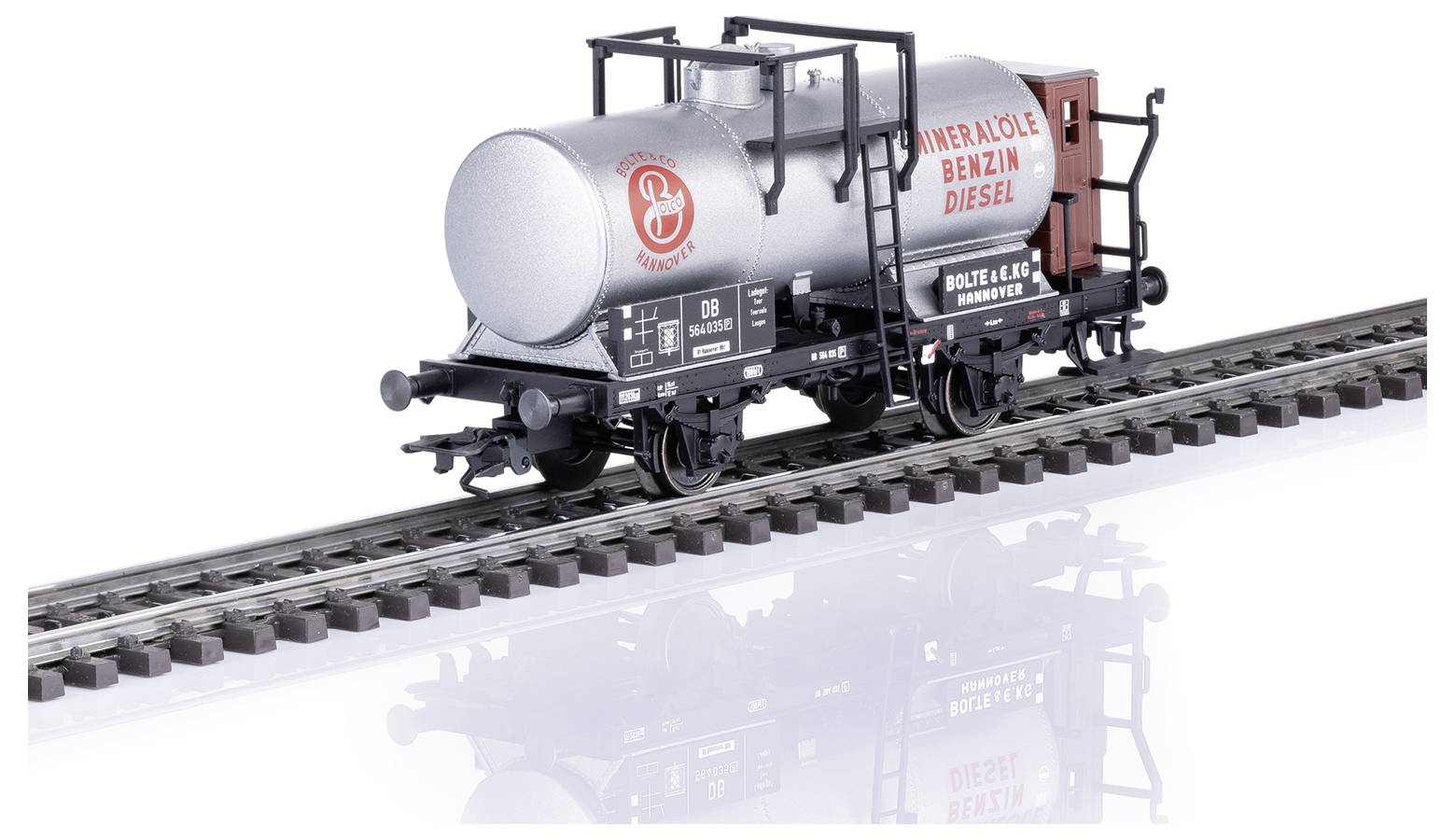 A goods wagon on rails, labelled 'MINERAL OIL PETROL DIESEL'. A silver tank with a German railway designation.