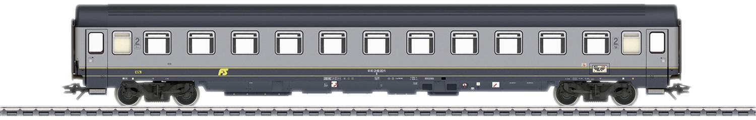 A grey train carriage with a yellow line and multiple windows stands on railway tracks. The carriage is elongated and has black wheels.