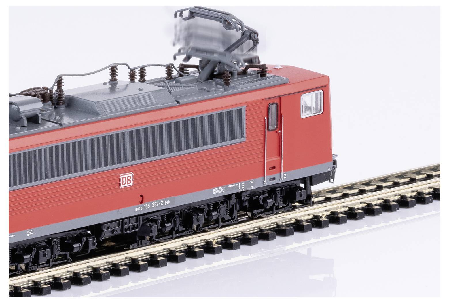 Red model of an electric locomotive from Deutsche Bahn on a section of track, side view from behind.