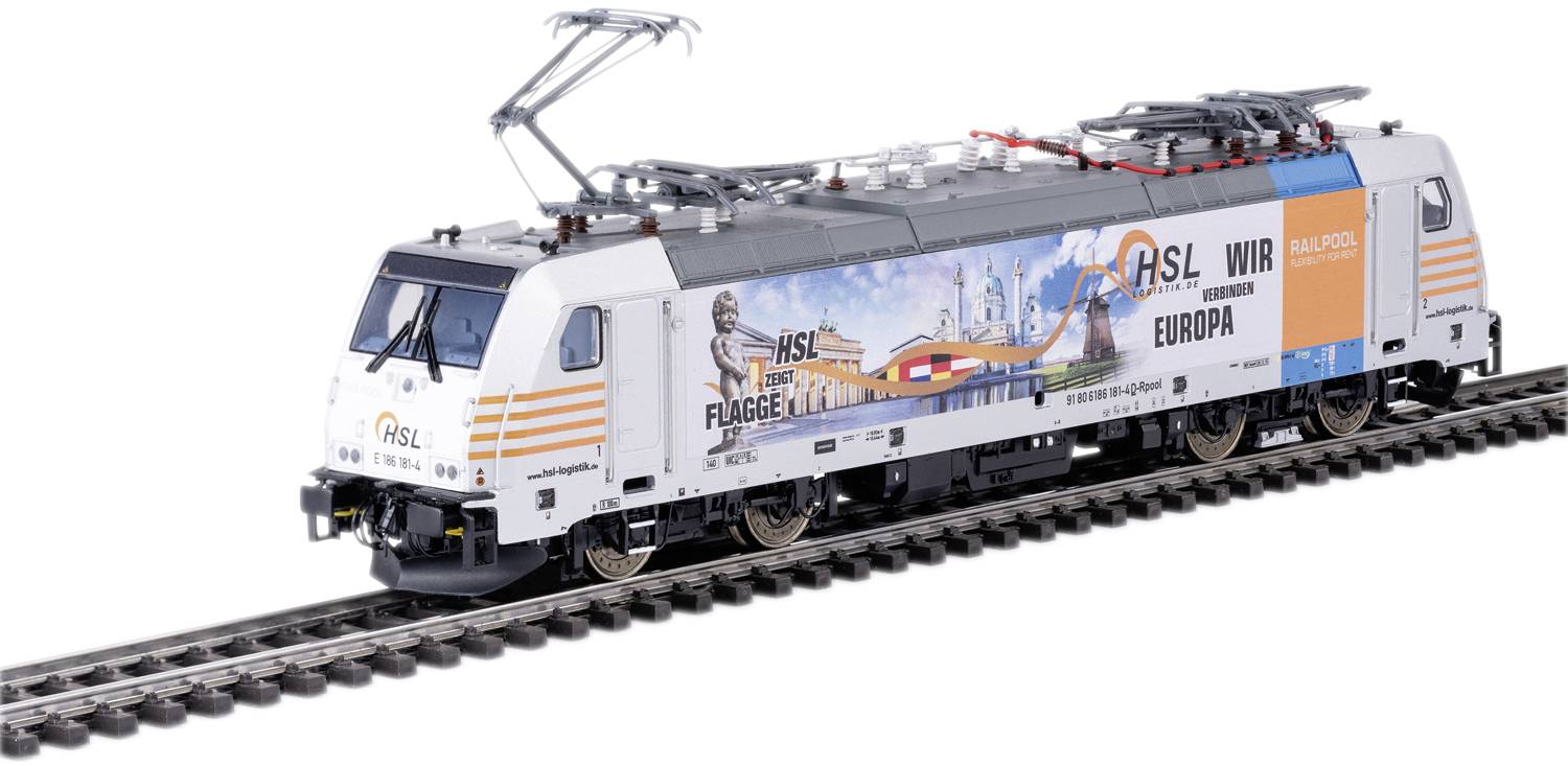 A white model train with the inscription 'HSL We Move Europe', displaying graphics of flags and a chimney. The train is positioned on a railway track.