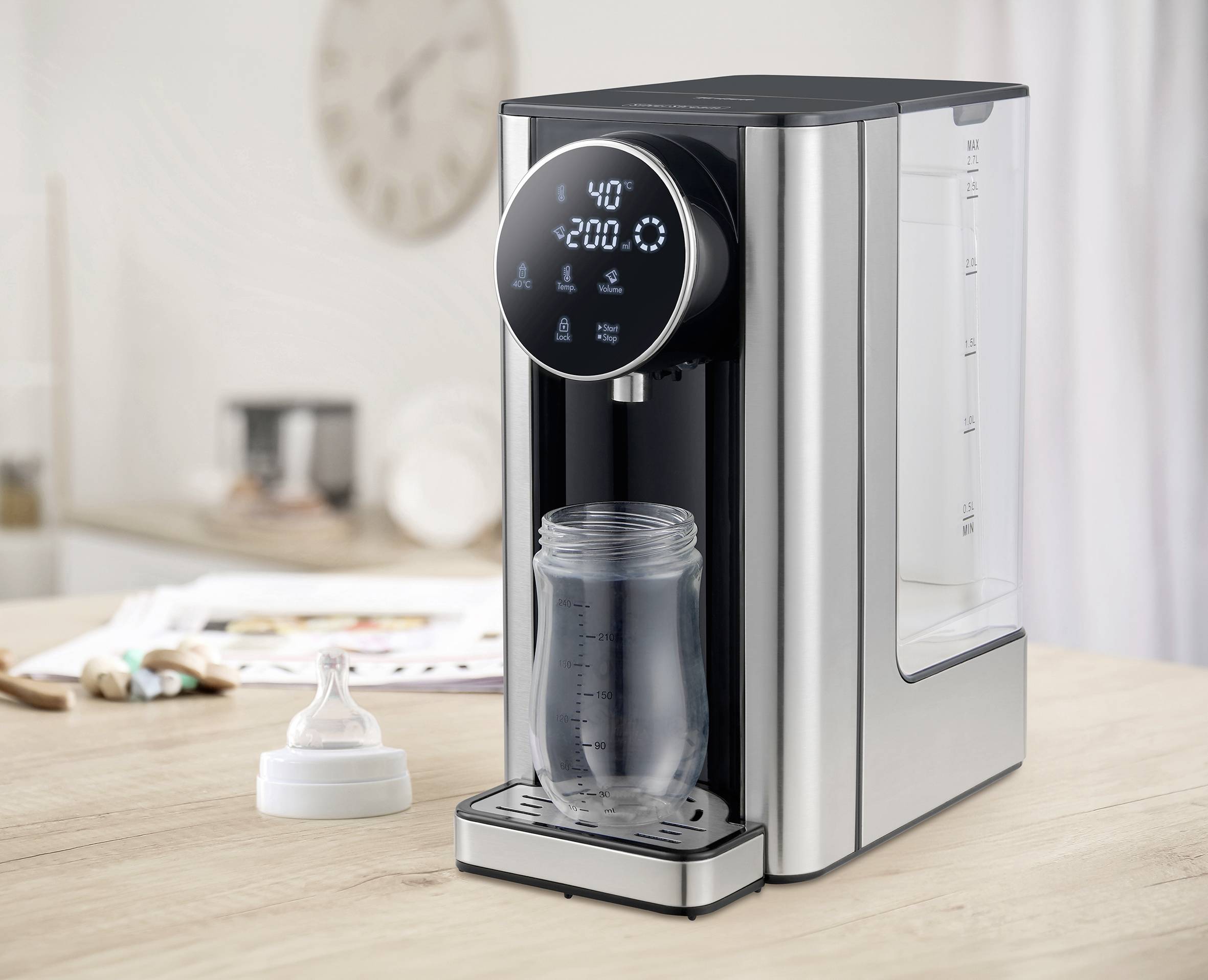 A kettle with a digital display shows 40°C. A glass is placed underneath, filled with hot water. A kitchen is visible in the background.