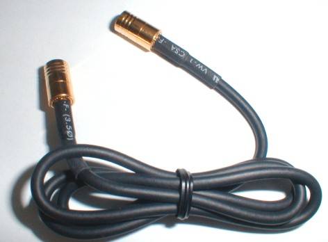 A black coaxial cable with two golden connectors, loosely coiled on a white background.