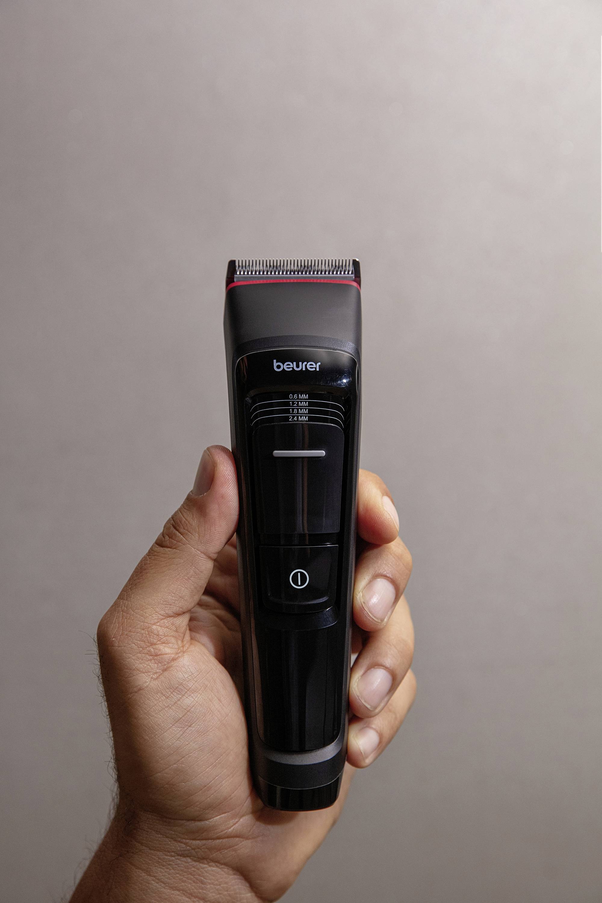 A hand is holding a sleek black electric hair clipper, ready for use.