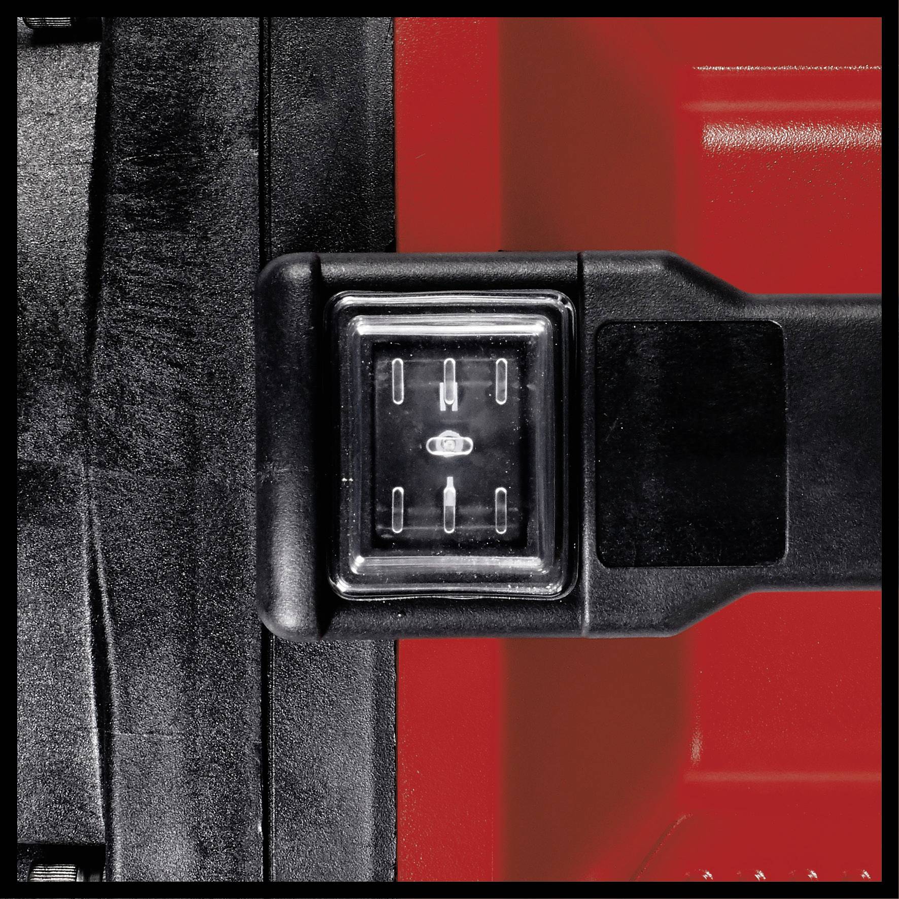 A close-up of a switch on a black device, surrounded by red surfaces. The switch displays four horizontal lines.