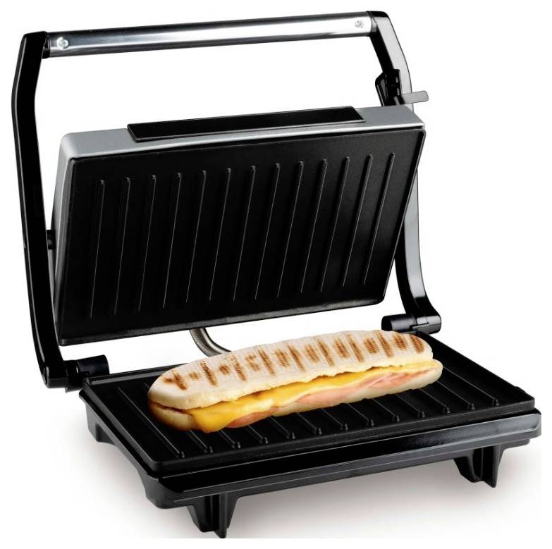 A panini press with a sandwich filled with cheese and ham. The grill has ribbed black plates.