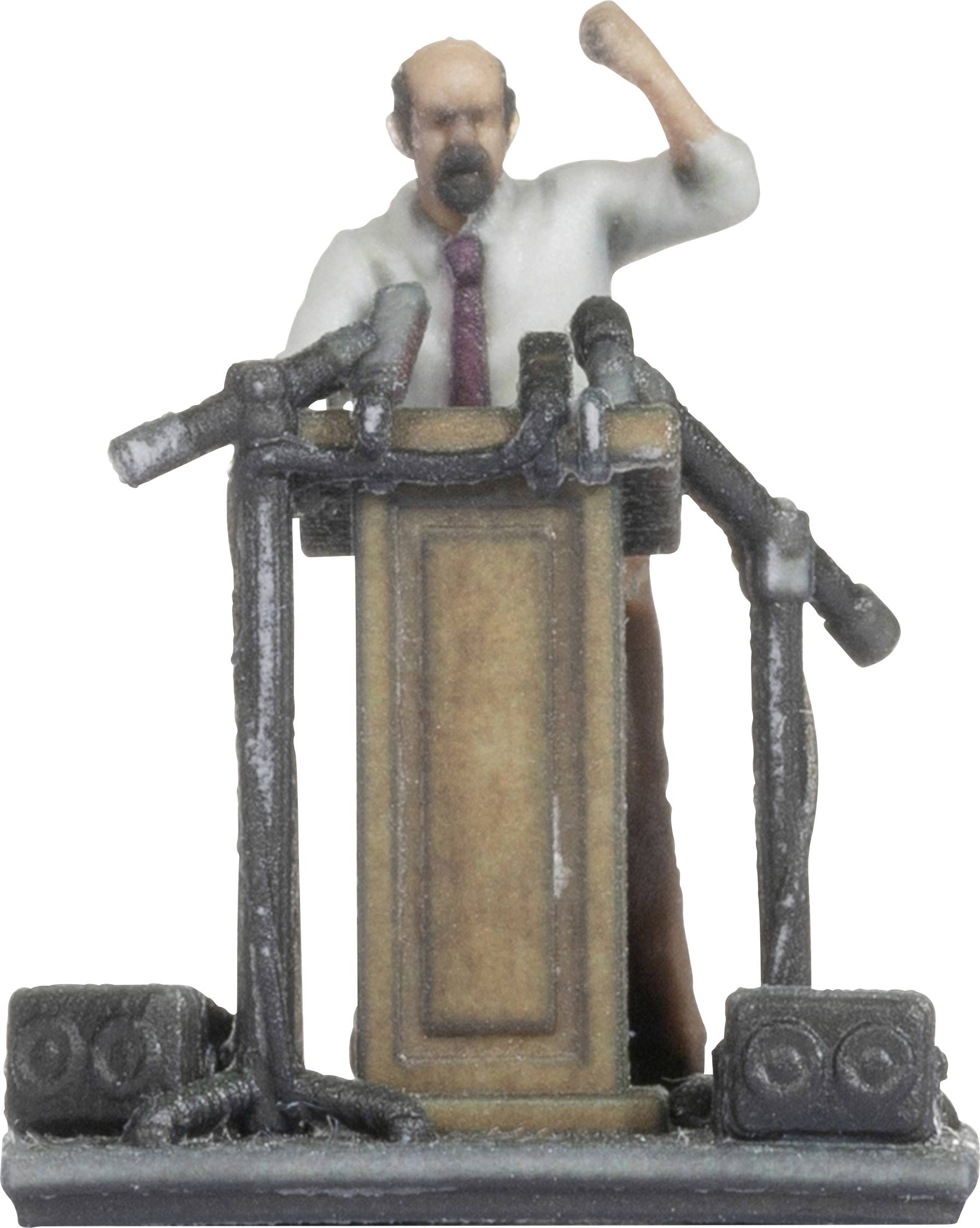 A miniature figurine stands behind a lectern, surrounded by microphones. The figure holds a fist in the air as if delivering a speech.