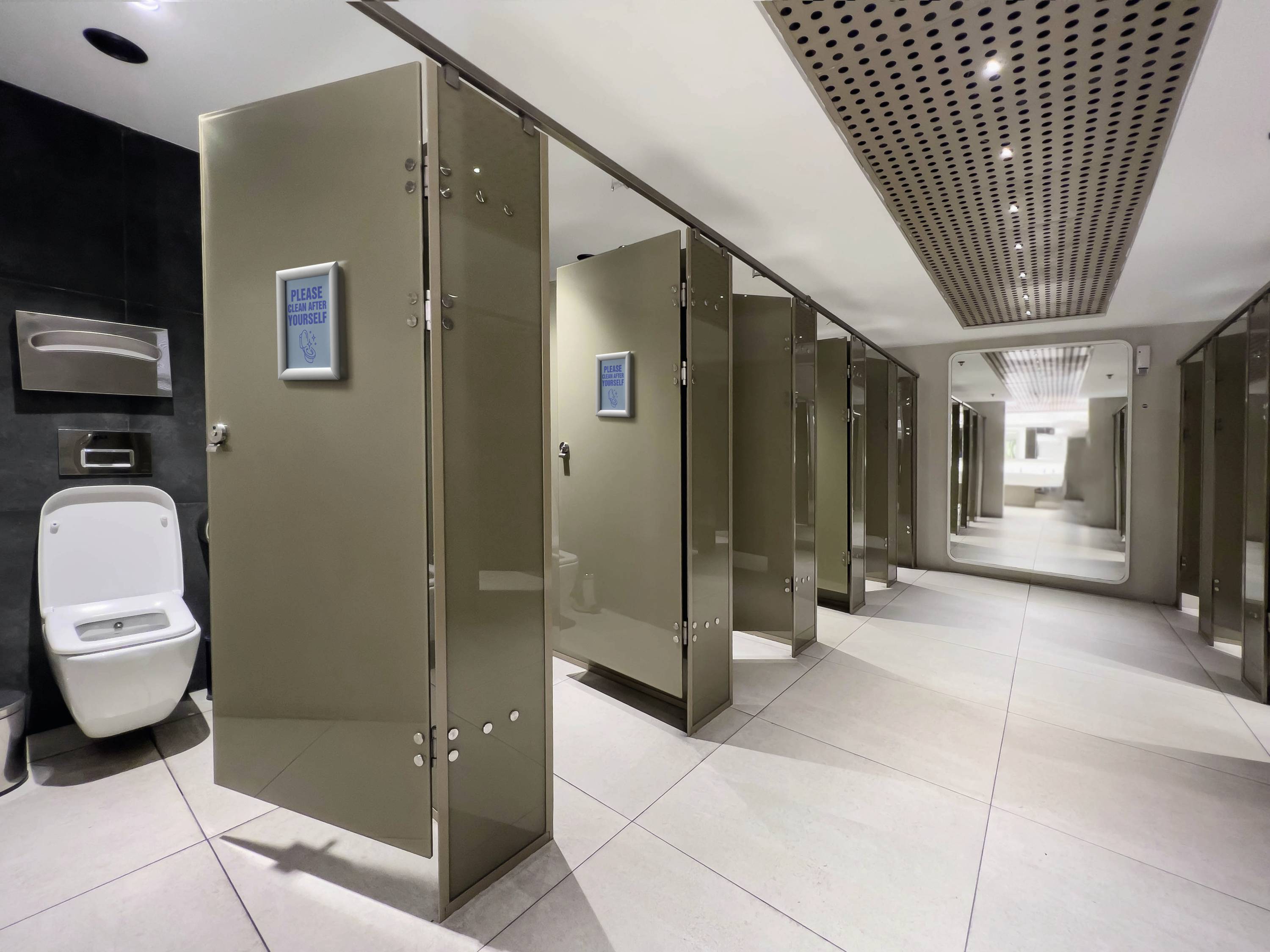 A modern, clean toilet facility with multiple cubicles and open doors; a washbasin area in the background.