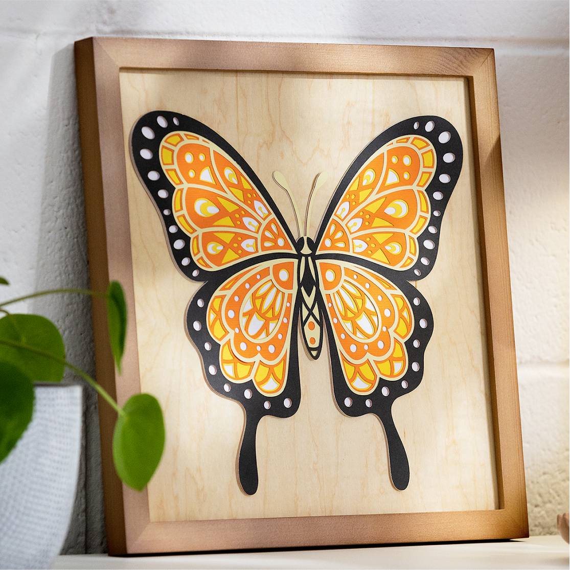 A framed picture of a stylised orange butterfly with black outlines and white accents on a wall.