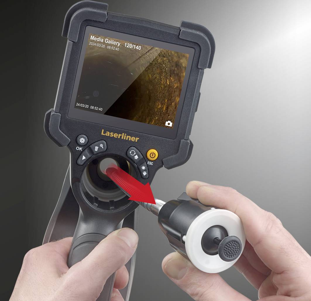 A person is holding an inspection camera with a screen displaying the interior of an object.