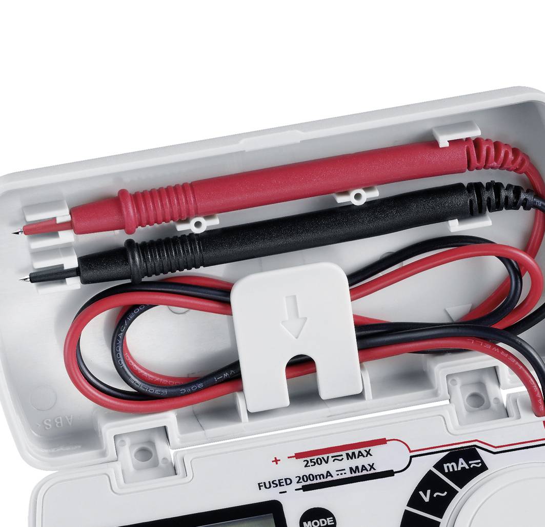 An open multimeter housing with red and black test leads. The cables are coiled and a fuse is inserted.