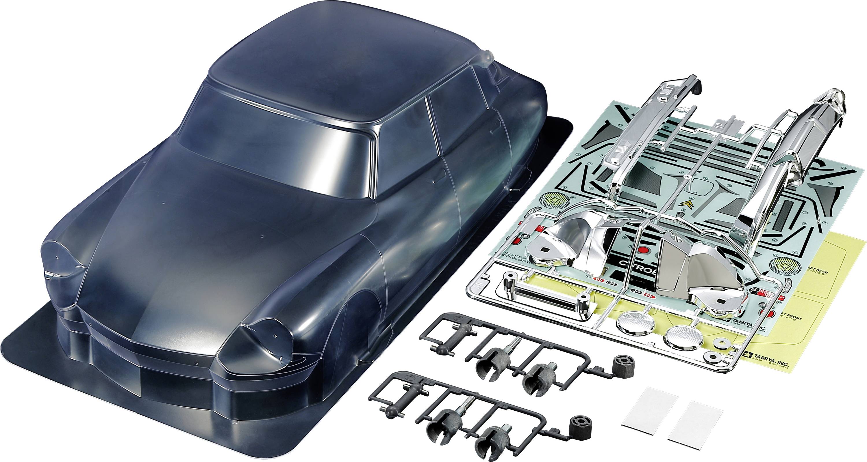 A model car kit with a clear bodywork and individual components laid out on a table, ready for assembly.