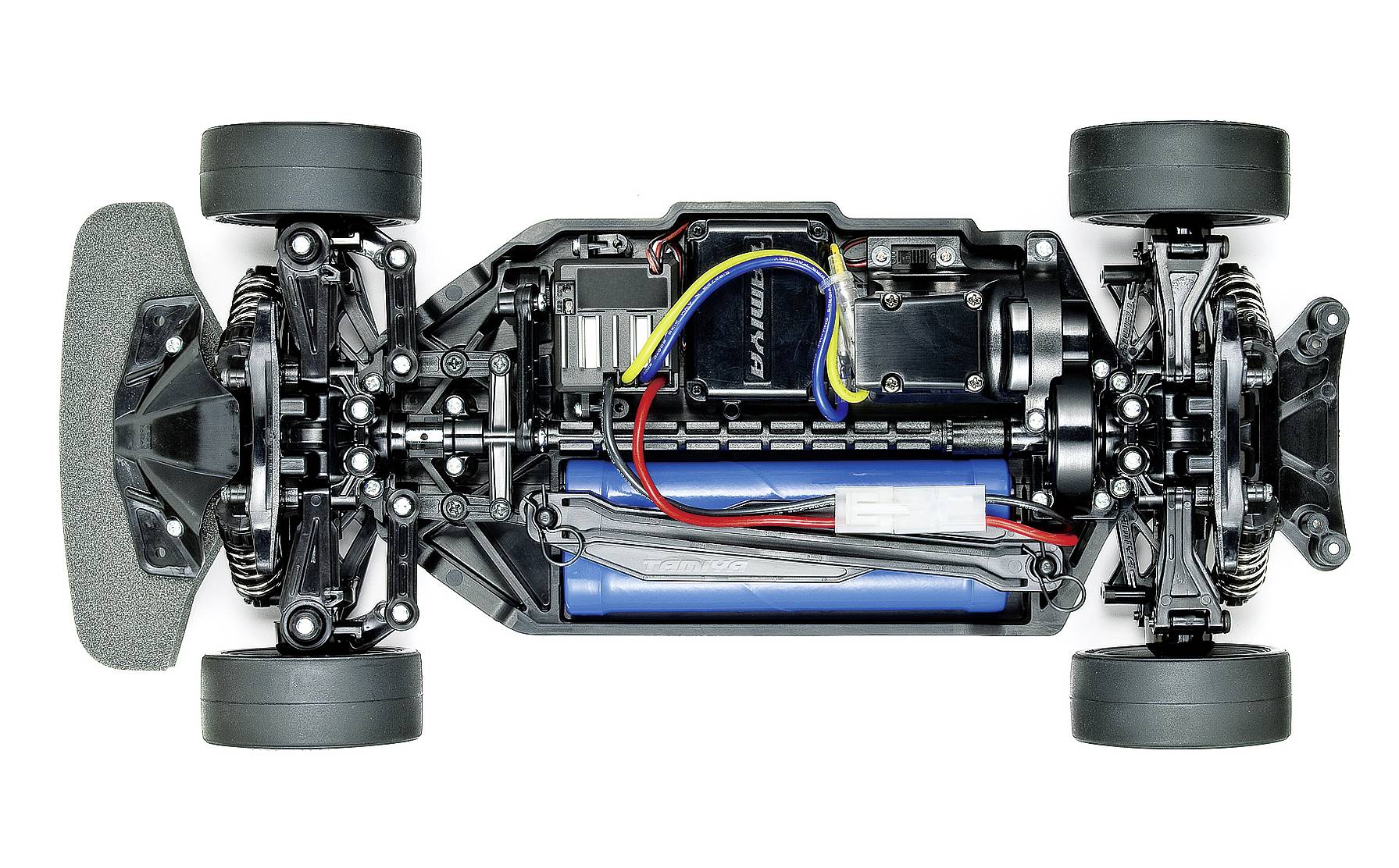 RC car chassis viewed from above, showing visible components: engine, wiring, batteries, and suspension. Four tyres on the left and right.