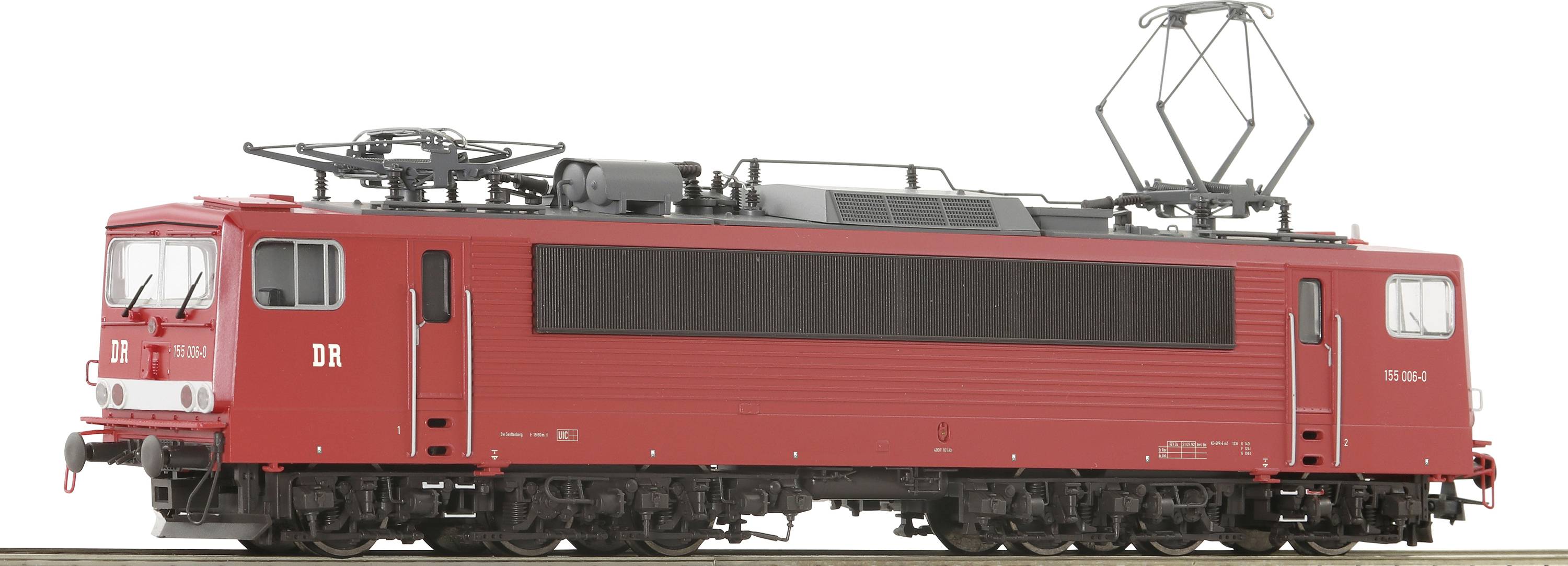 A red electric locomotive of Deutsche Reichsbahn with the inscription 'DR' stands sideways. It has a rectangular design.